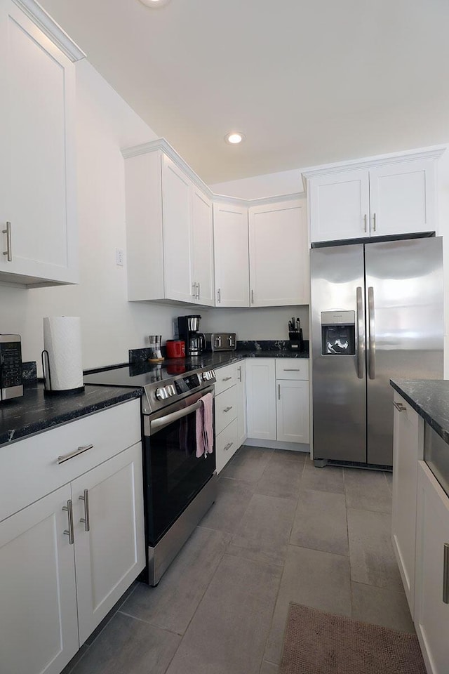 kitchen with light tile patterned flooring, recessed lighting, white cabinets, appliances with stainless steel finishes, and dark stone counters