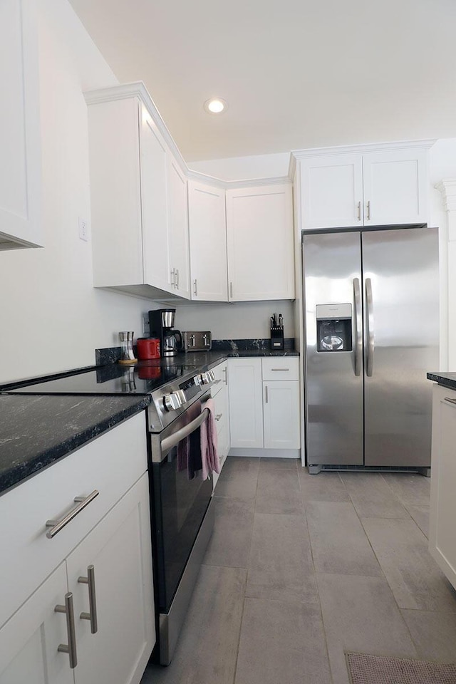 kitchen featuring light tile patterned floors, recessed lighting, appliances with stainless steel finishes, white cabinets, and dark stone countertops