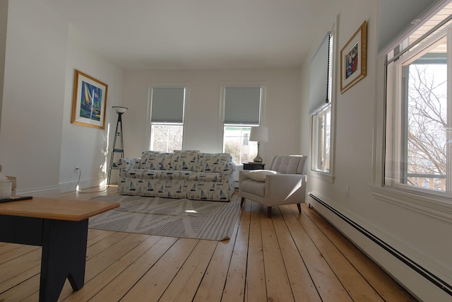 living area with a wealth of natural light, a baseboard radiator, light wood-style flooring, and baseboards