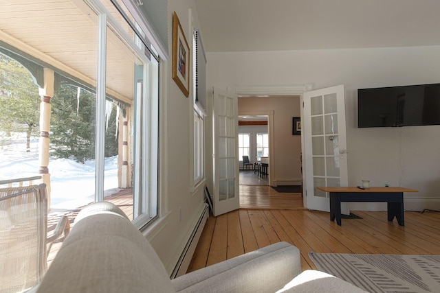 hallway with french doors, baseboard heating, and light wood-style flooring