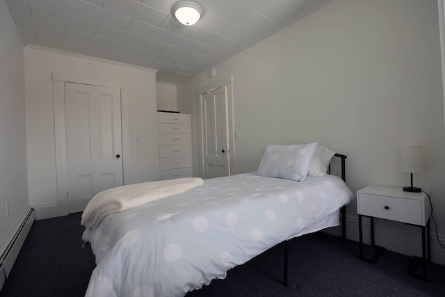 bedroom with baseboard heating, dark carpet, a closet, and crown molding