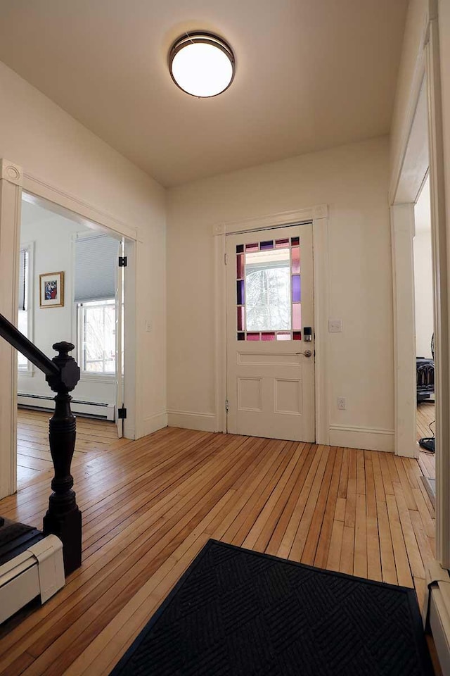 entryway with light wood-style floors, baseboards, and a baseboard heating unit