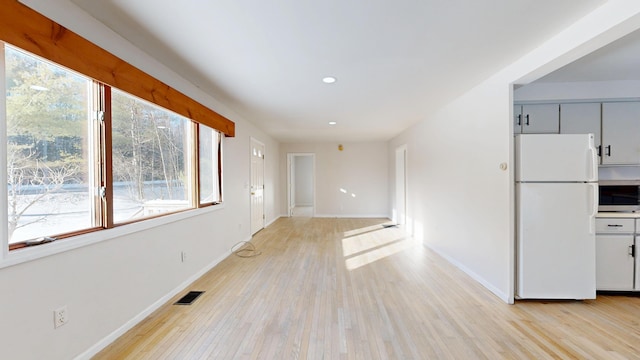 interior space with light wood-style flooring, visible vents, and baseboards