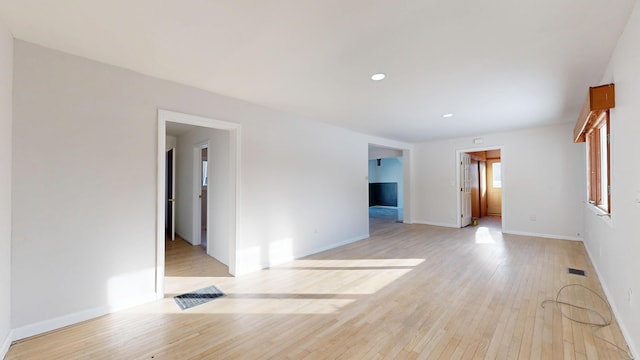 spare room featuring light wood-style floors, recessed lighting, visible vents, and baseboards