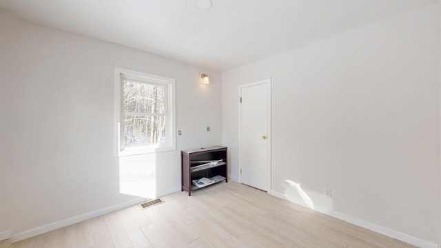 empty room with light wood-type flooring, visible vents, and baseboards