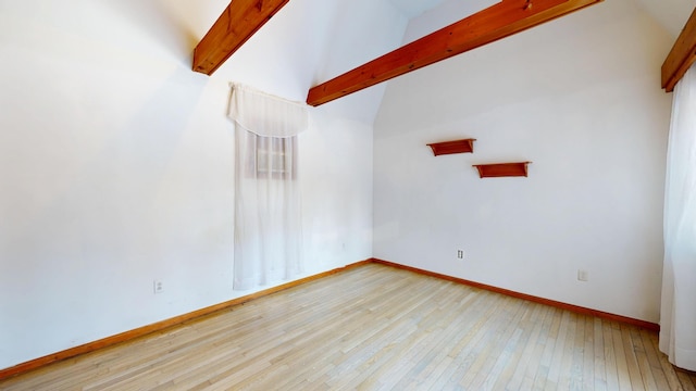 spare room featuring vaulted ceiling with beams, light wood finished floors, and baseboards