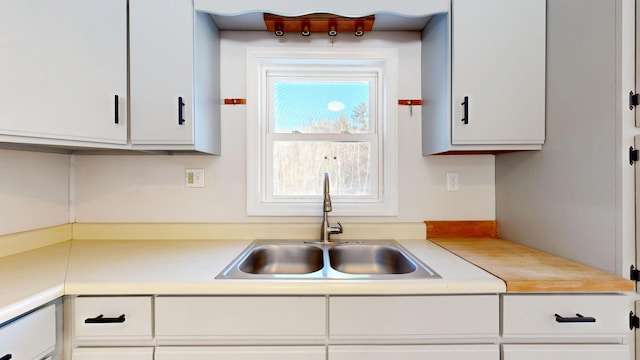 kitchen featuring white cabinets, light countertops, and a sink