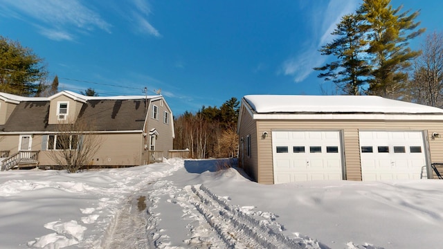 snow covered property with a garage and a gambrel roof