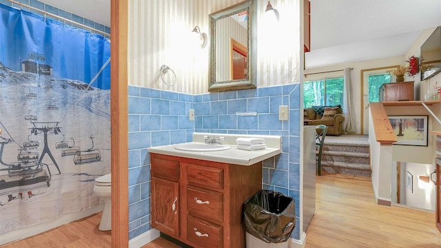 full bathroom featuring curtained shower, toilet, wood finished floors, vanity, and tile walls