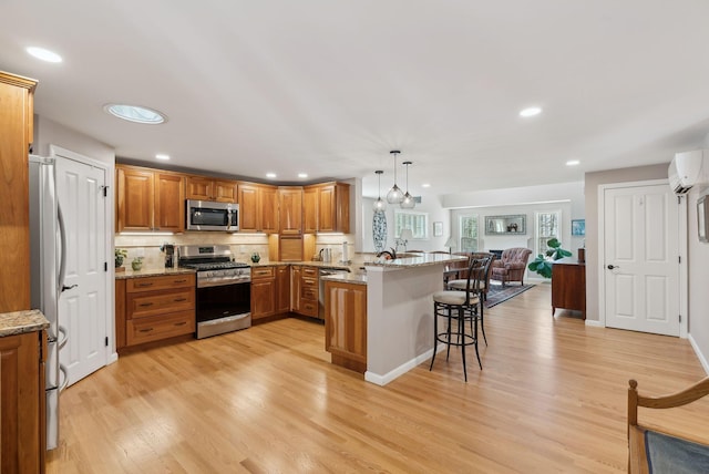 kitchen featuring a breakfast bar, stainless steel appliances, a wall mounted AC, open floor plan, and a peninsula