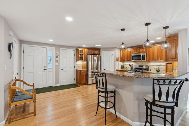 kitchen featuring stainless steel appliances, a breakfast bar area, a peninsula, and brown cabinets