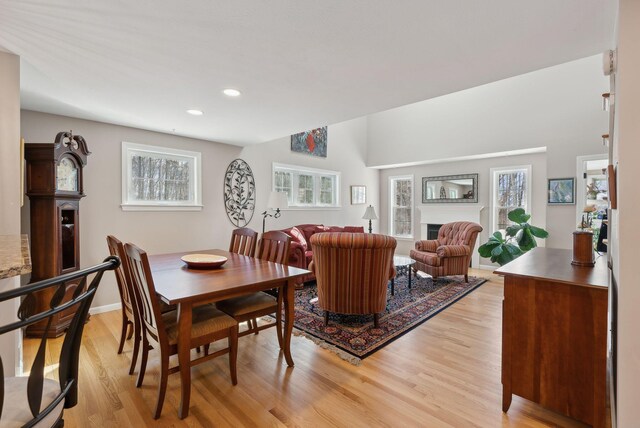 dining area featuring light wood-style floors, recessed lighting, a fireplace, and baseboards