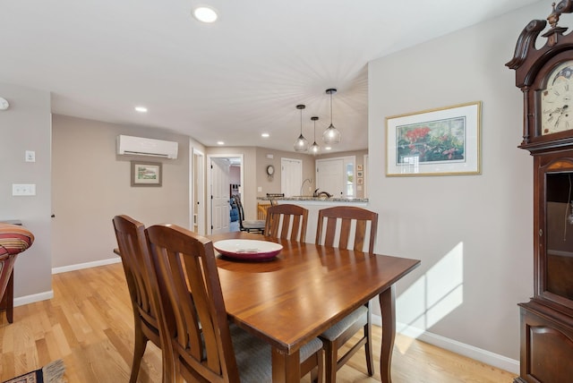 dining area with recessed lighting, baseboards, a wall mounted air conditioner, and light wood finished floors