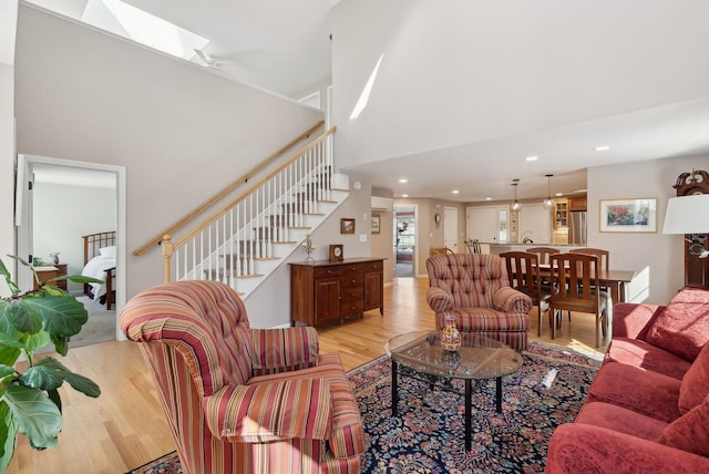 living area featuring recessed lighting, a high ceiling, a skylight, stairs, and light wood-type flooring