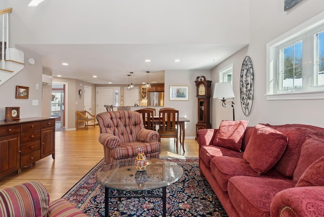 living room featuring recessed lighting, baseboards, stairs, light wood-style floors, and a wall mounted AC