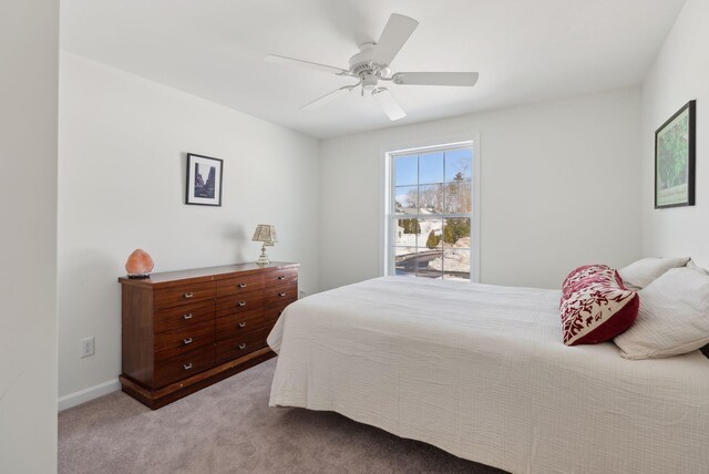 carpeted bedroom with ceiling fan and baseboards