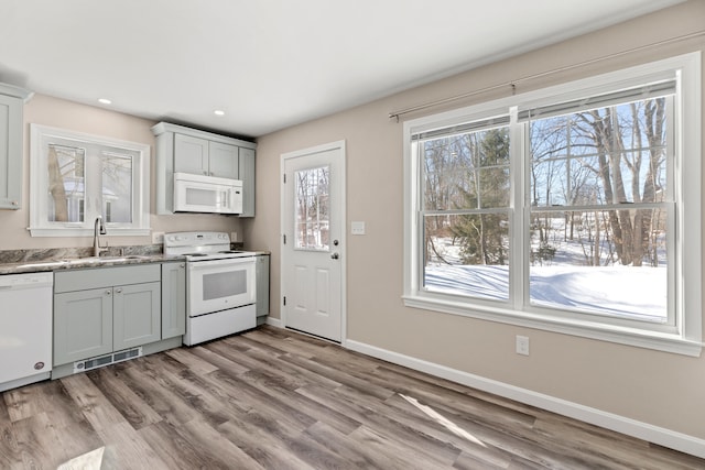 kitchen featuring white appliances, baseboards, light countertops, light wood-style floors, and a sink