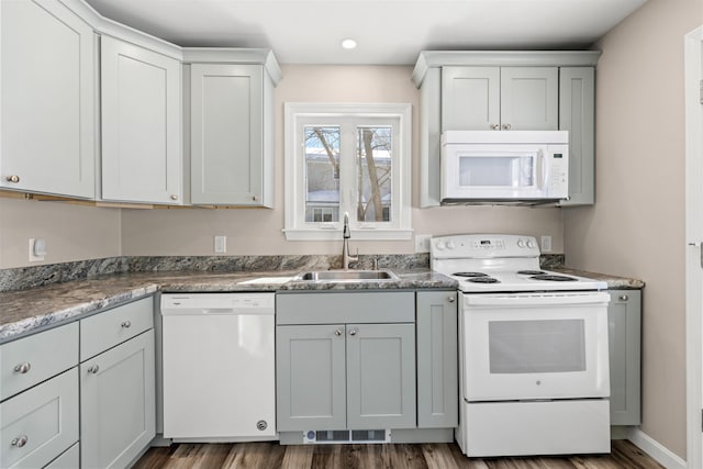 kitchen with white appliances, baseboards, a sink, and dark wood-style flooring