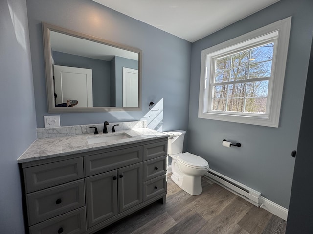 half bath featuring toilet, wood finished floors, vanity, baseboards, and baseboard heating