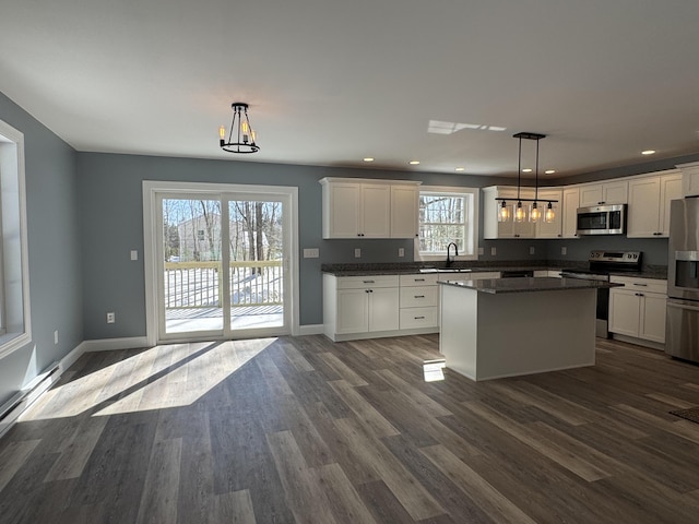 kitchen featuring appliances with stainless steel finishes, a sink, white cabinets, and pendant lighting