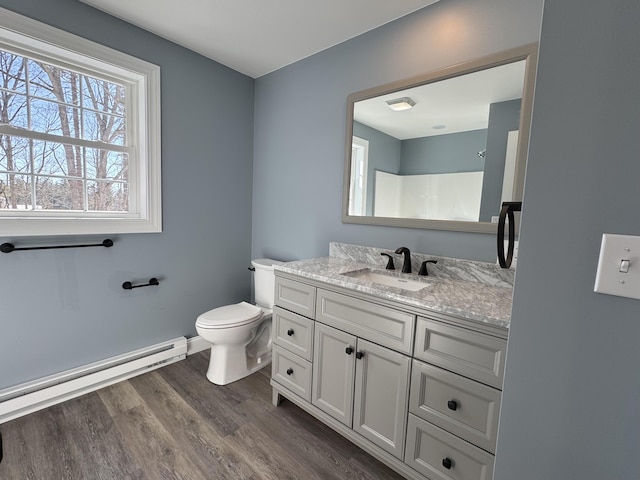 bathroom with a baseboard radiator, toilet, vanity, wood finished floors, and baseboards