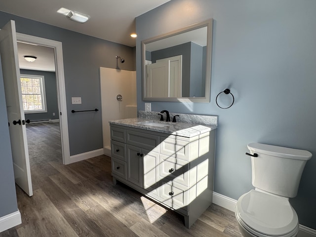 bathroom featuring baseboards, a shower, toilet, wood finished floors, and vanity