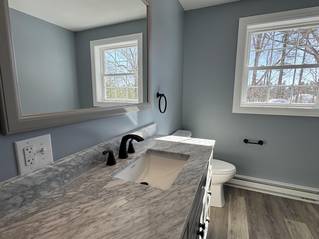 half bath featuring toilet, a baseboard radiator, wood finished floors, and vanity