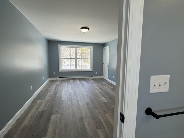 empty room with a baseboard heating unit, dark wood-type flooring, and baseboards