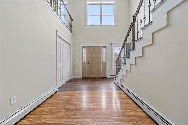 foyer featuring plenty of natural light, baseboard heating, and wood finished floors