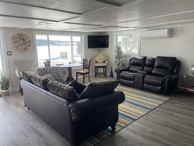 living area with a wealth of natural light, baseboards, wood finished floors, and a wall mounted AC