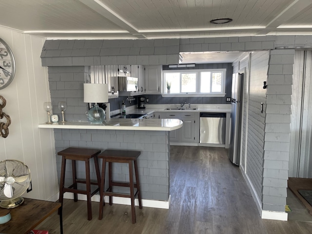 kitchen with white cabinets, appliances with stainless steel finishes, a peninsula, light countertops, and a kitchen bar