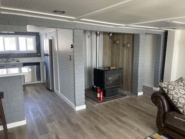 interior space with a sink, a wood stove, baseboards, and wood finished floors