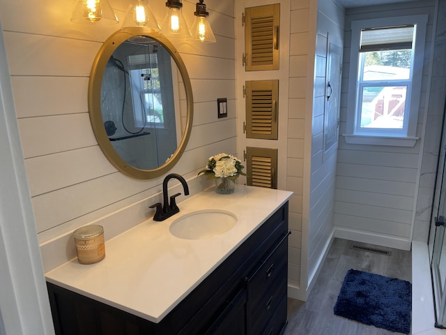 bathroom featuring wooden walls, visible vents, wood finished floors, and vanity