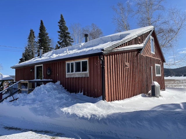 view of snow covered exterior featuring board and batten siding and central air condition unit