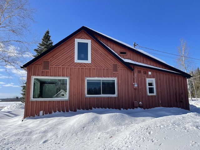 view of snowy exterior featuring board and batten siding and a garage