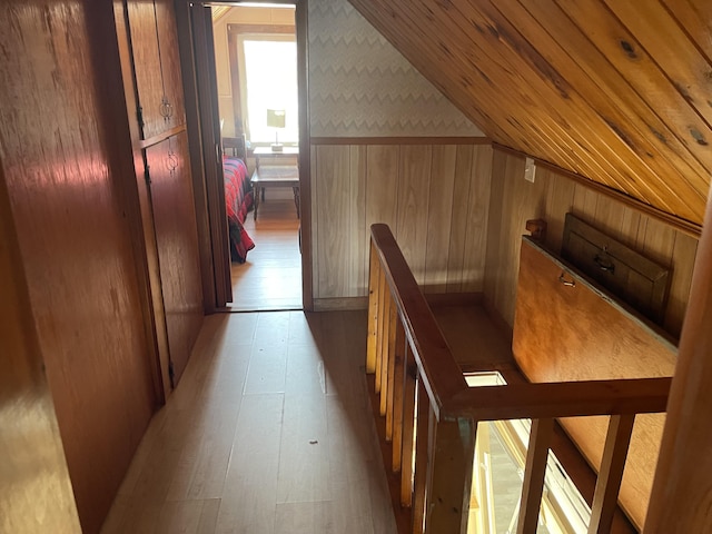 corridor featuring wood finished floors, an upstairs landing, and wooden walls