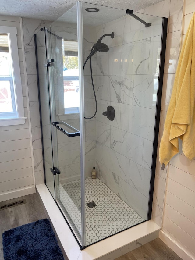 full bath with a stall shower, baseboards, visible vents, wood finished floors, and a textured ceiling