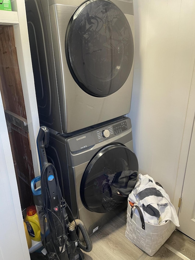 washroom with laundry area, stacked washing maching and dryer, and wood finished floors