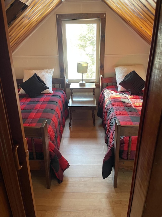 bedroom with lofted ceiling and light wood-style floors