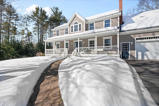 view of front of home with a porch, a chimney, and a garage