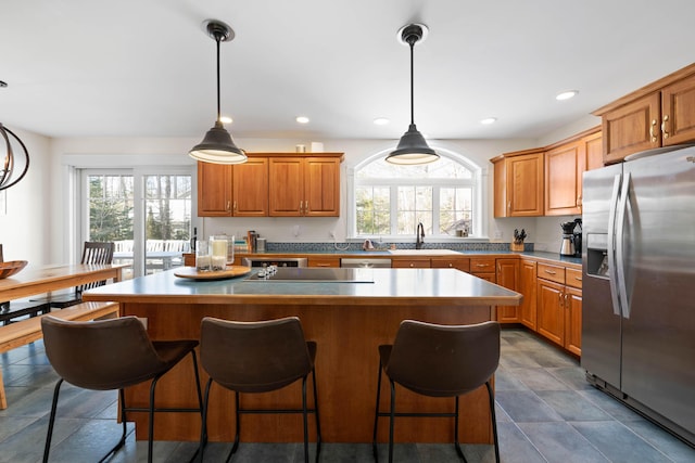 kitchen featuring stainless steel refrigerator with ice dispenser, a sink, a wealth of natural light, and a center island