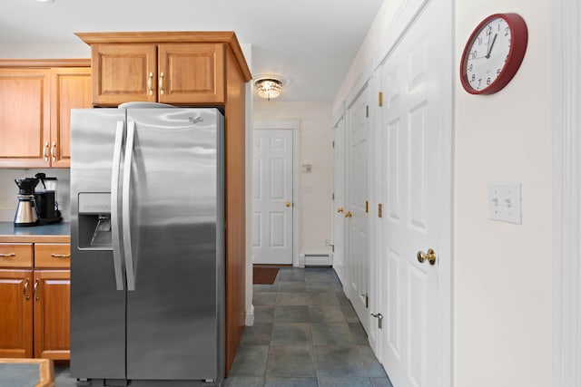 kitchen with brown cabinets, stainless steel refrigerator with ice dispenser, baseboard heating, and dark tile patterned floors