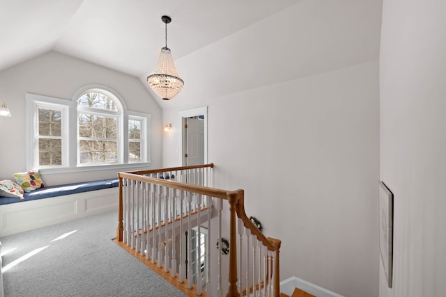 hall with vaulted ceiling, carpet, a chandelier, and an upstairs landing