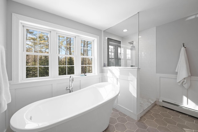 bathroom featuring wainscoting, a baseboard radiator, a freestanding bath, a walk in shower, and a decorative wall