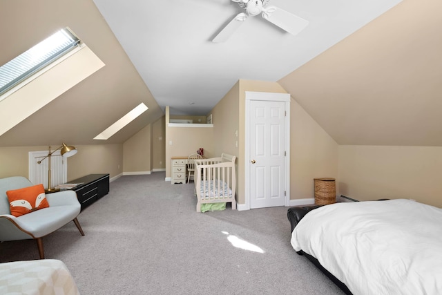 carpeted bedroom featuring vaulted ceiling with skylight, ceiling fan, and baseboards