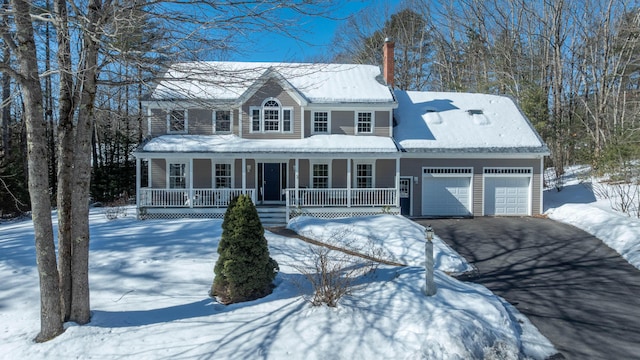 view of front of property featuring a garage, a porch, a chimney, and aphalt driveway