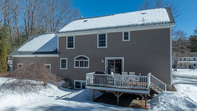 snow covered rear of property with a deck