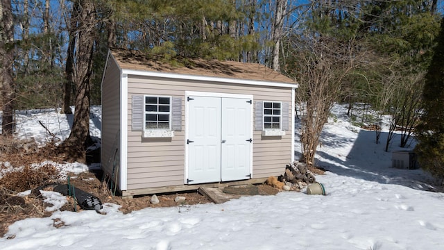 snow covered structure featuring an outdoor structure and a shed