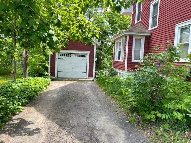 view of property exterior with a garage, an outbuilding, and aphalt driveway