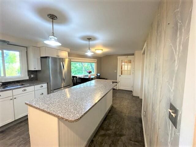 kitchen with white cabinets, hanging light fixtures, freestanding refrigerator, and a center island